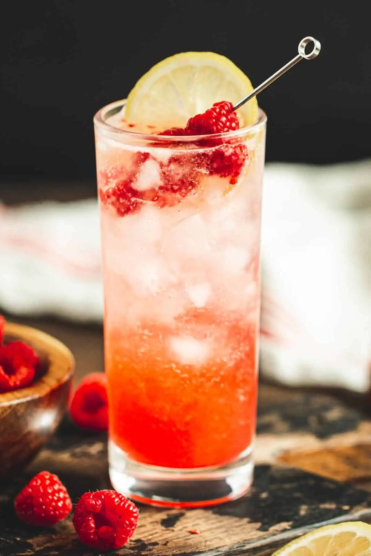 Raspberry collins garnished with fresh raspberries and lemon.