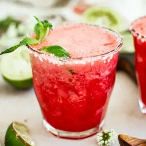 Raspberry margarita with a salted rim and mint leaf for garnish.