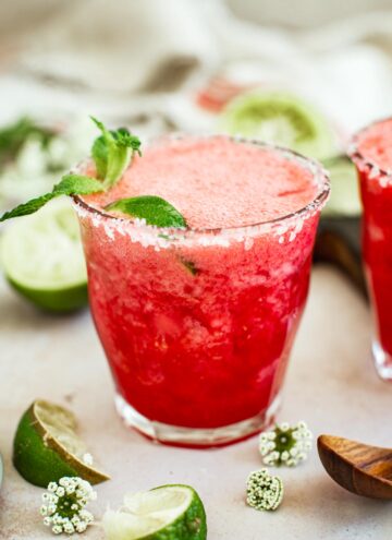 Raspberry margarita with a salted rim and mint leaf for garnish.