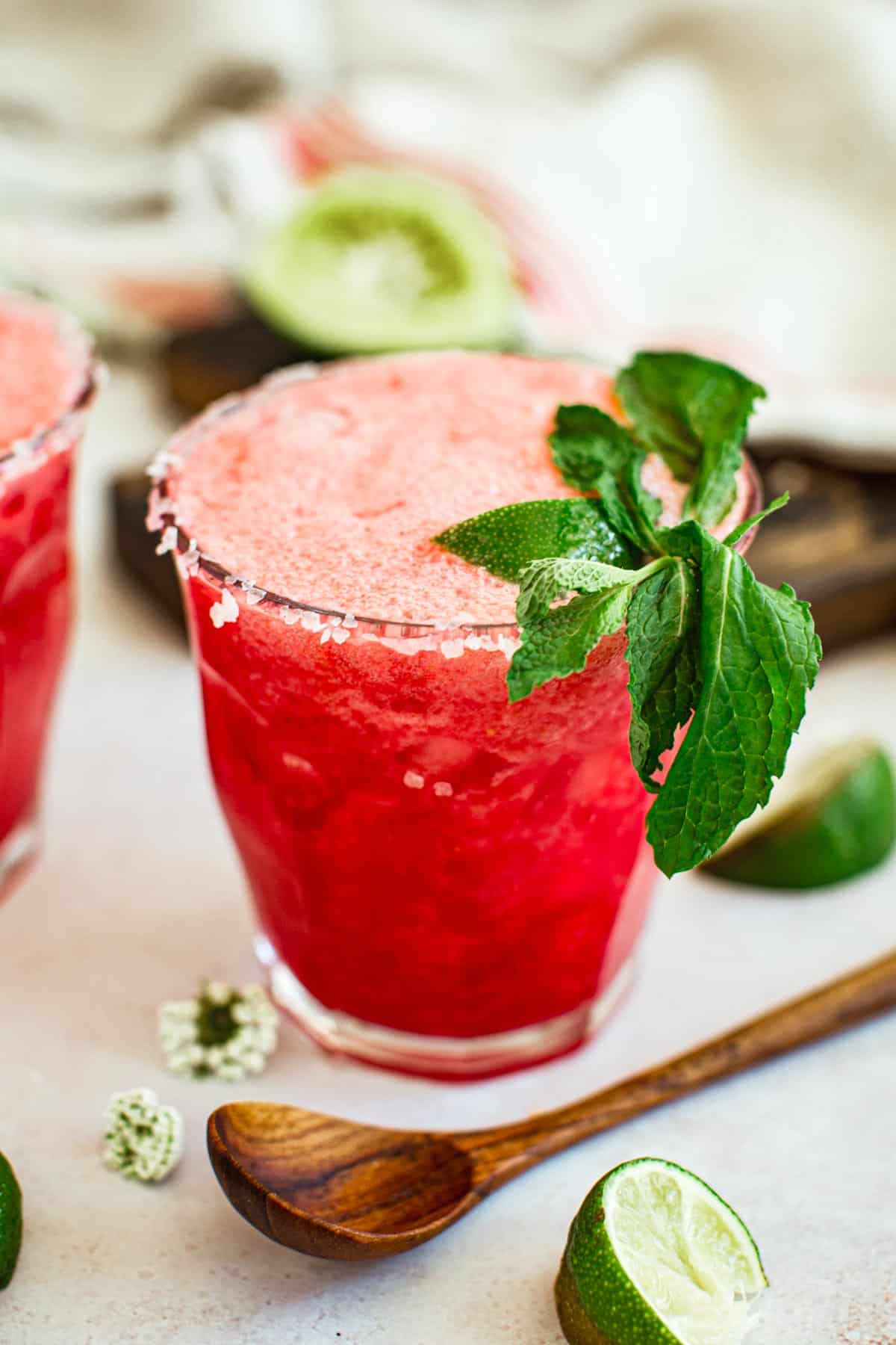 Raspberry margarita with a salted rim and mint leaves for garnish.