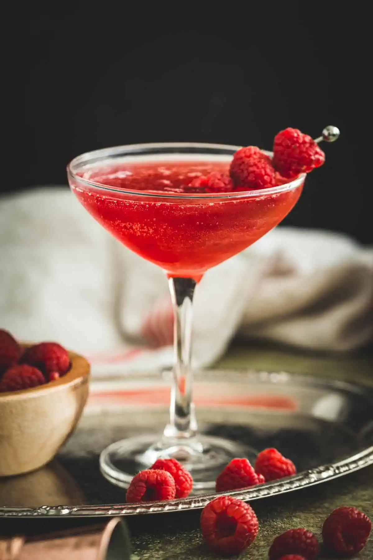 Raspberry martini with fresh raspberries on a cocktail skewer.