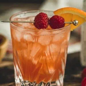 Raspberry sour cocktail with fresh raspberries for garnish.