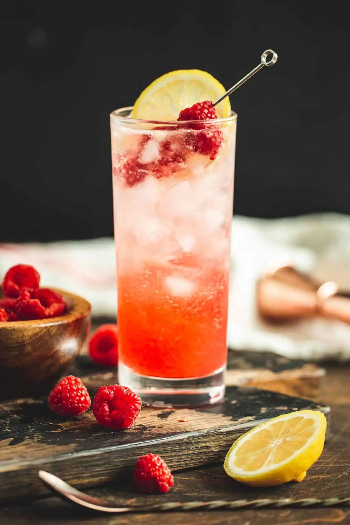 Raspberry Tom Collins garnished with fresh raspberry and lemon.