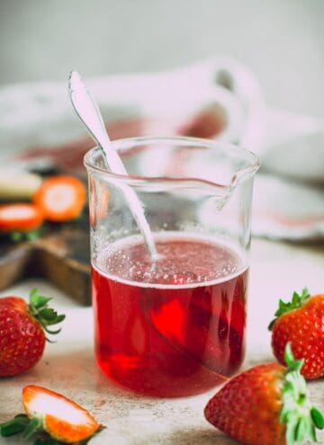 Strawberry simple syrup in a jar with a spoon inside.