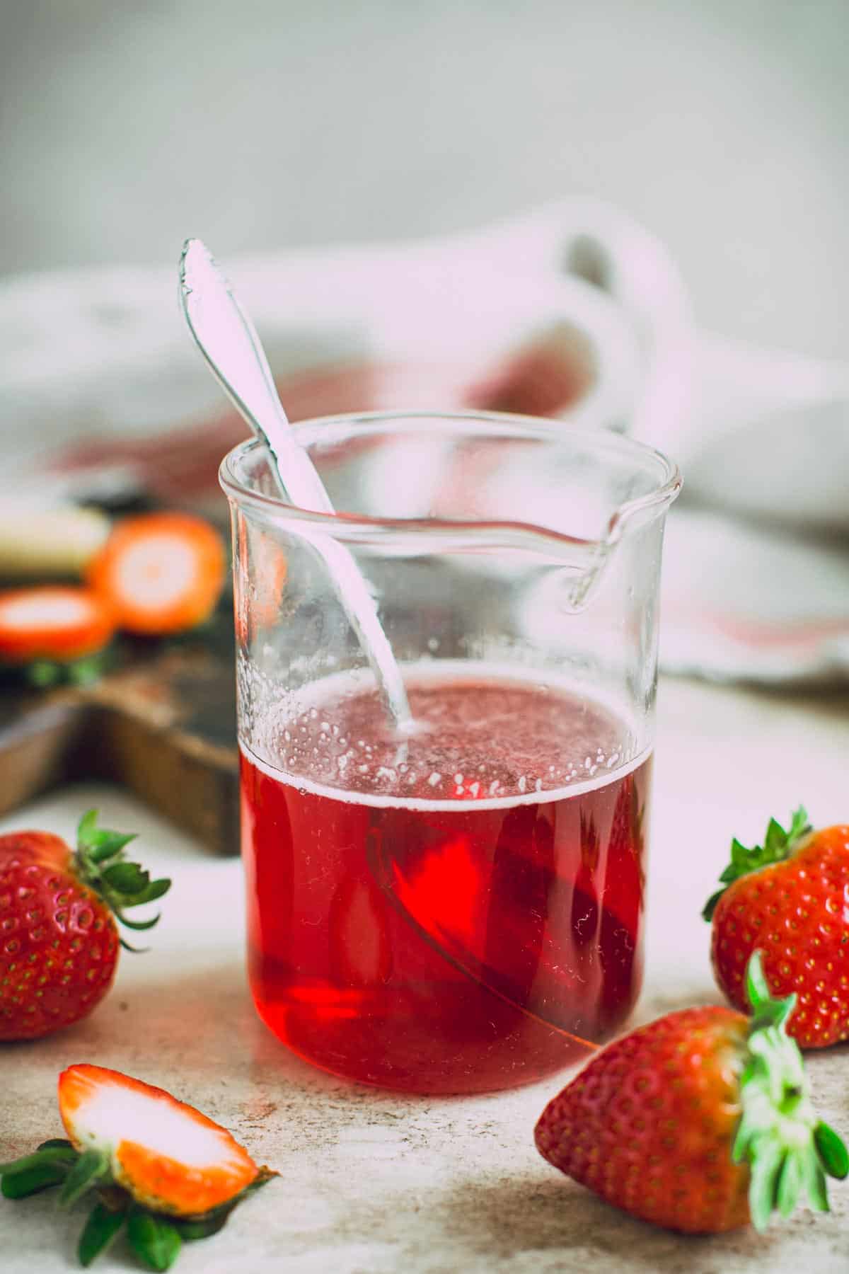 Strawberry simple syrup in a jar with a spoon inside.