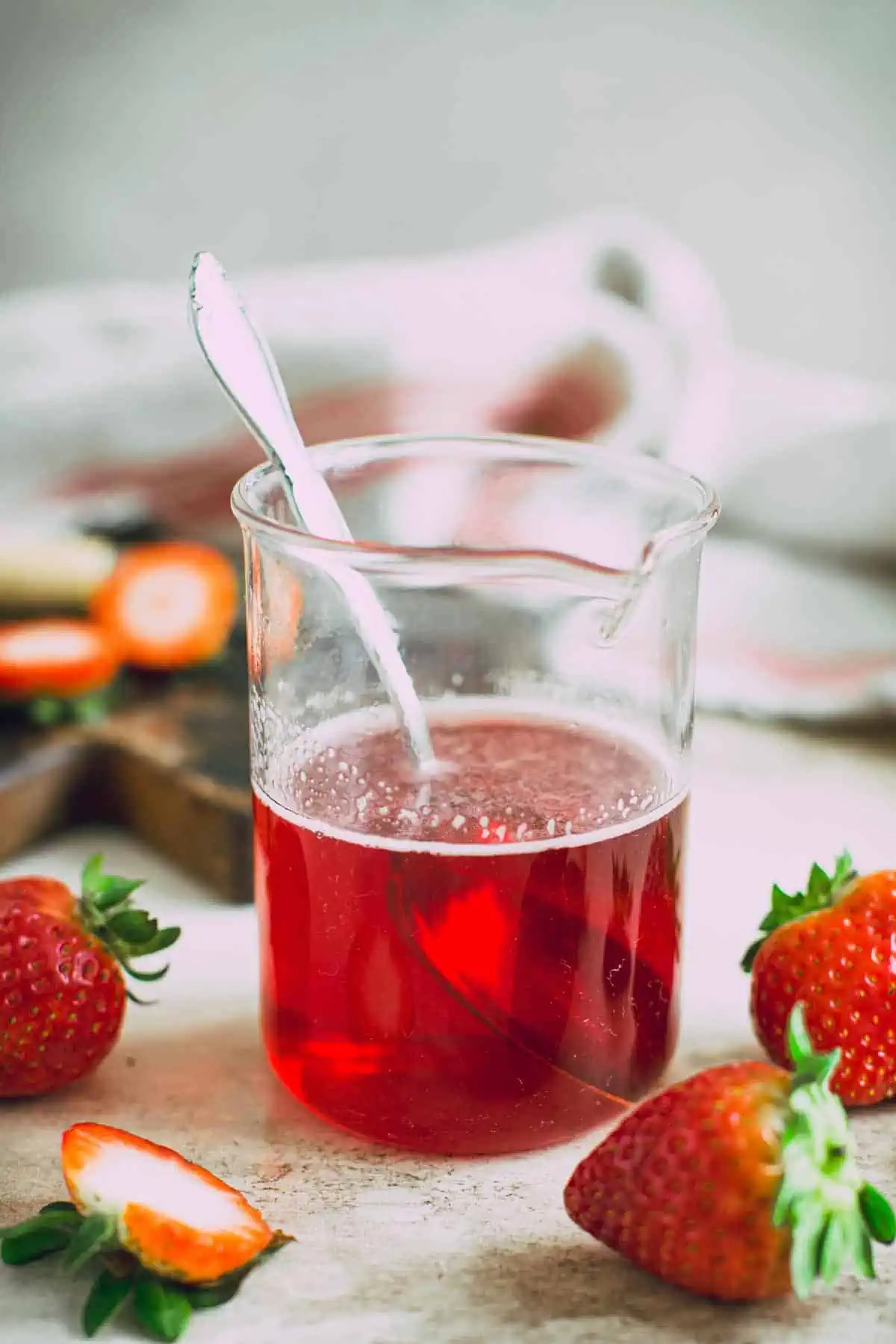 Strawberry simple syrup in a jar with a spoon inside.