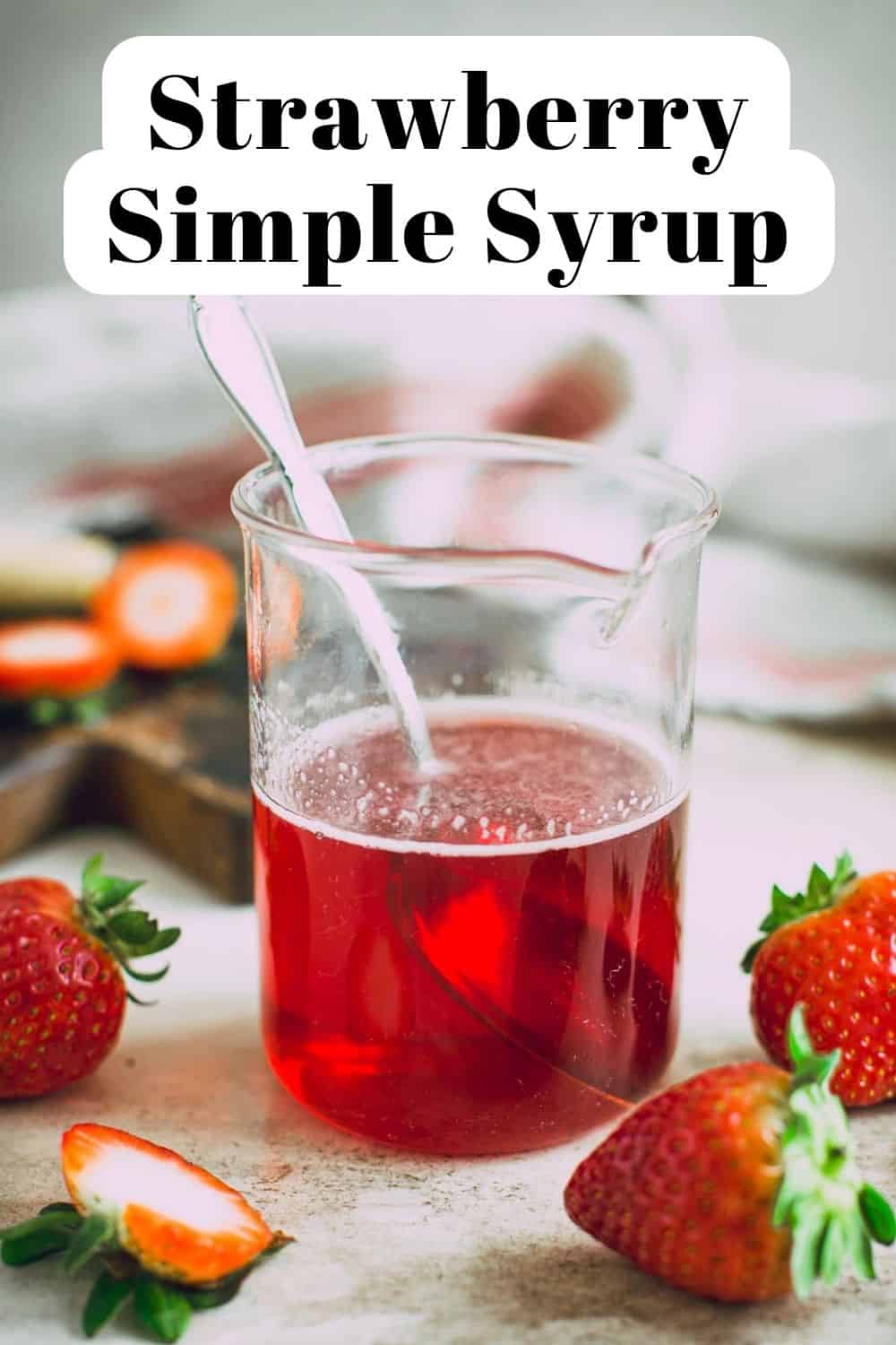 Strawberry simple syrup for cocktails in a glass jar with a spoon.