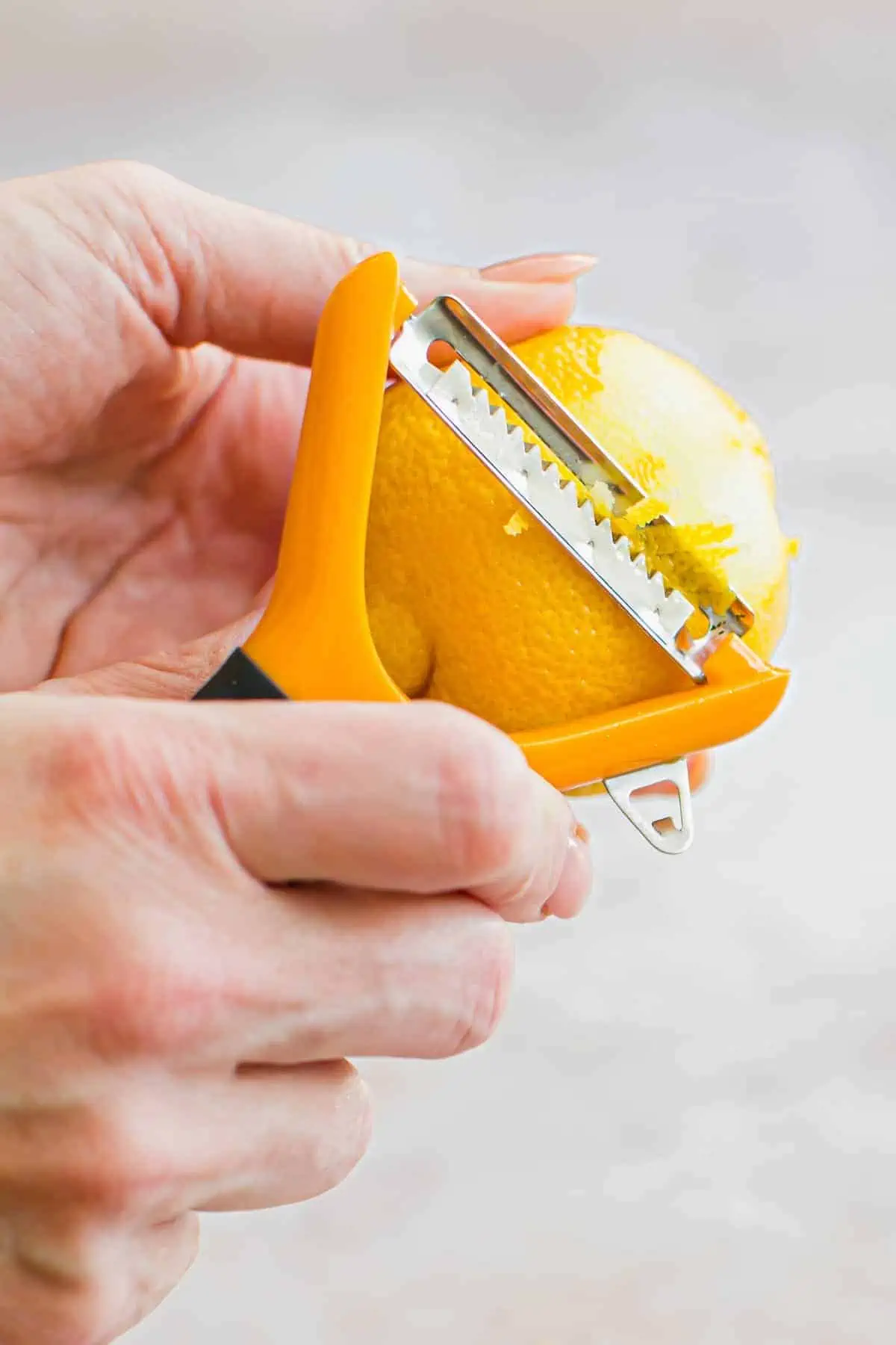 Zesting a lemon using a julienne peeler.