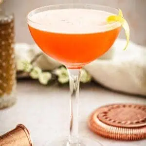 Aperol sour with a lemon peel garnish.