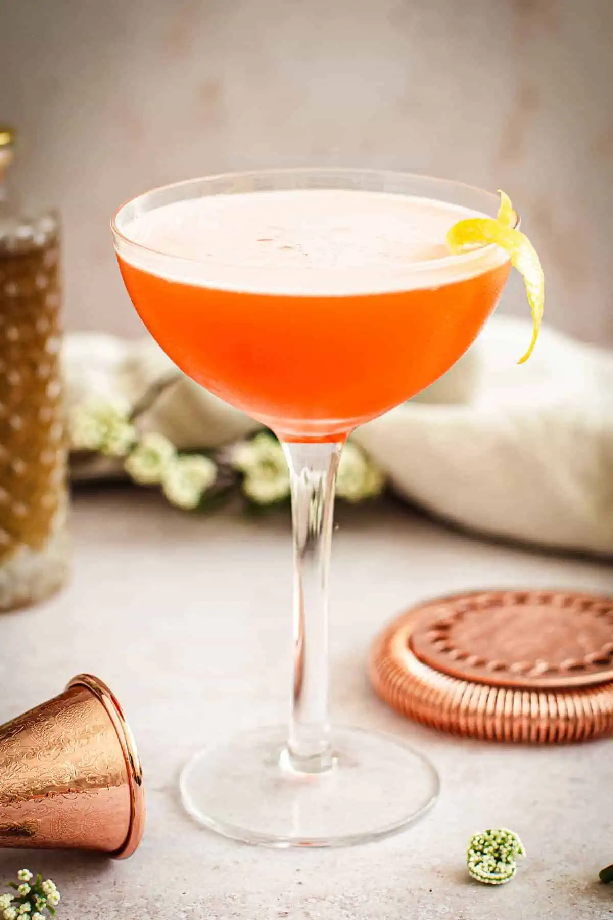 Aperol sour with a lemon peel garnish.