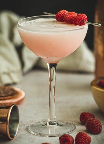 Clover club cocktail garnished with fresh raspberries.