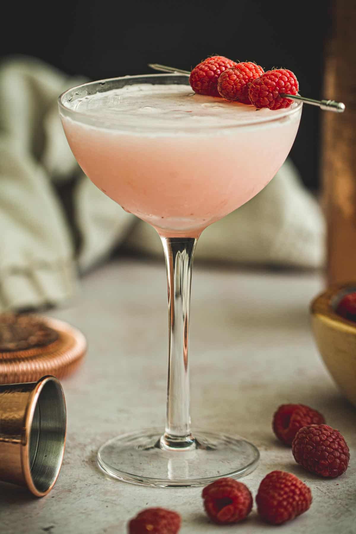 Clover club cocktail garnished with fresh raspberries.