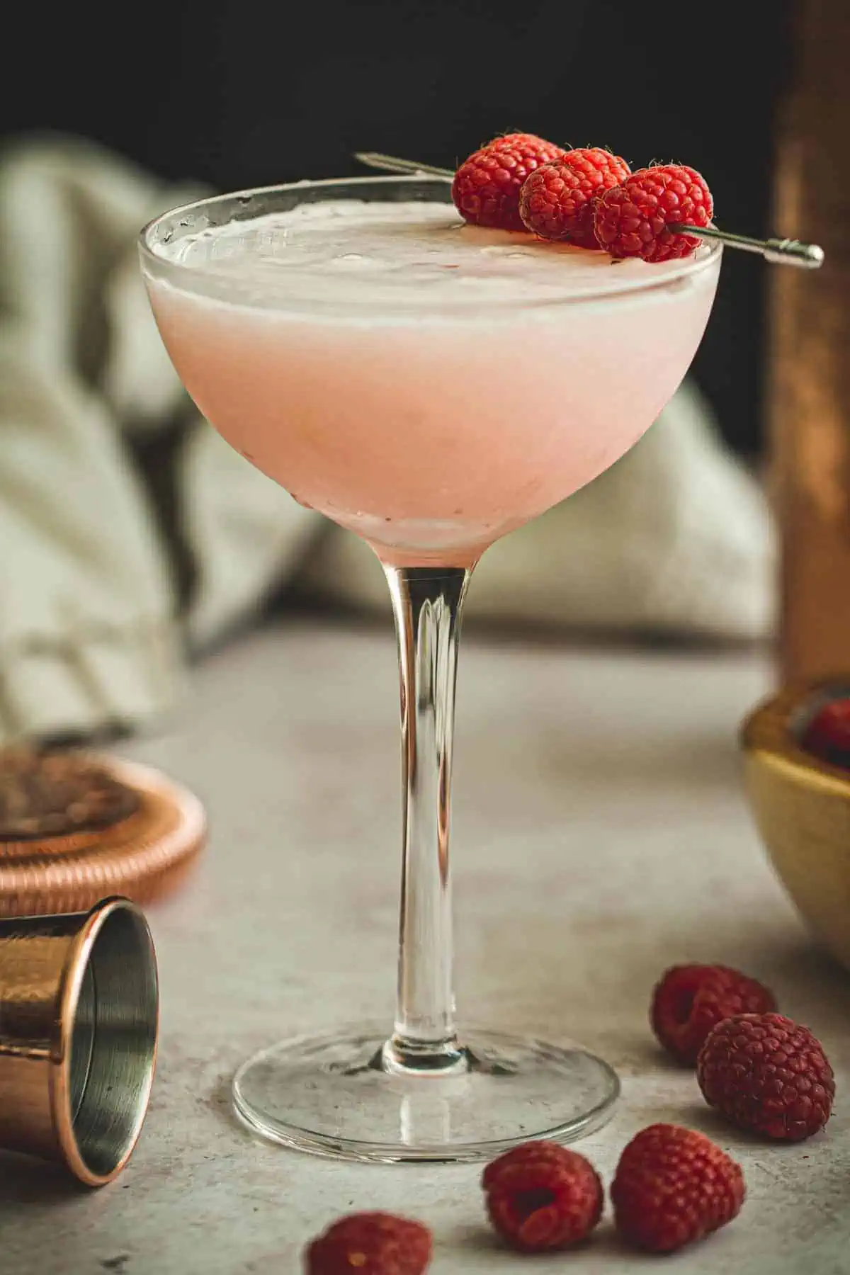 Clover club cocktail garnished with fresh raspberries.