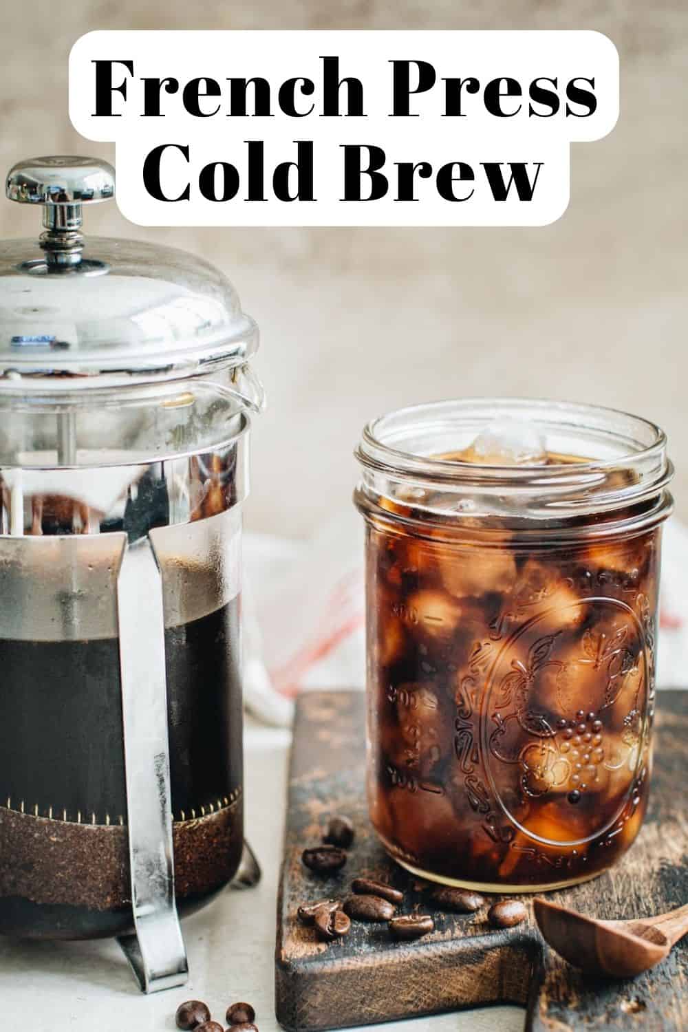 Cold brew coffee in a mason jar next to a French press.