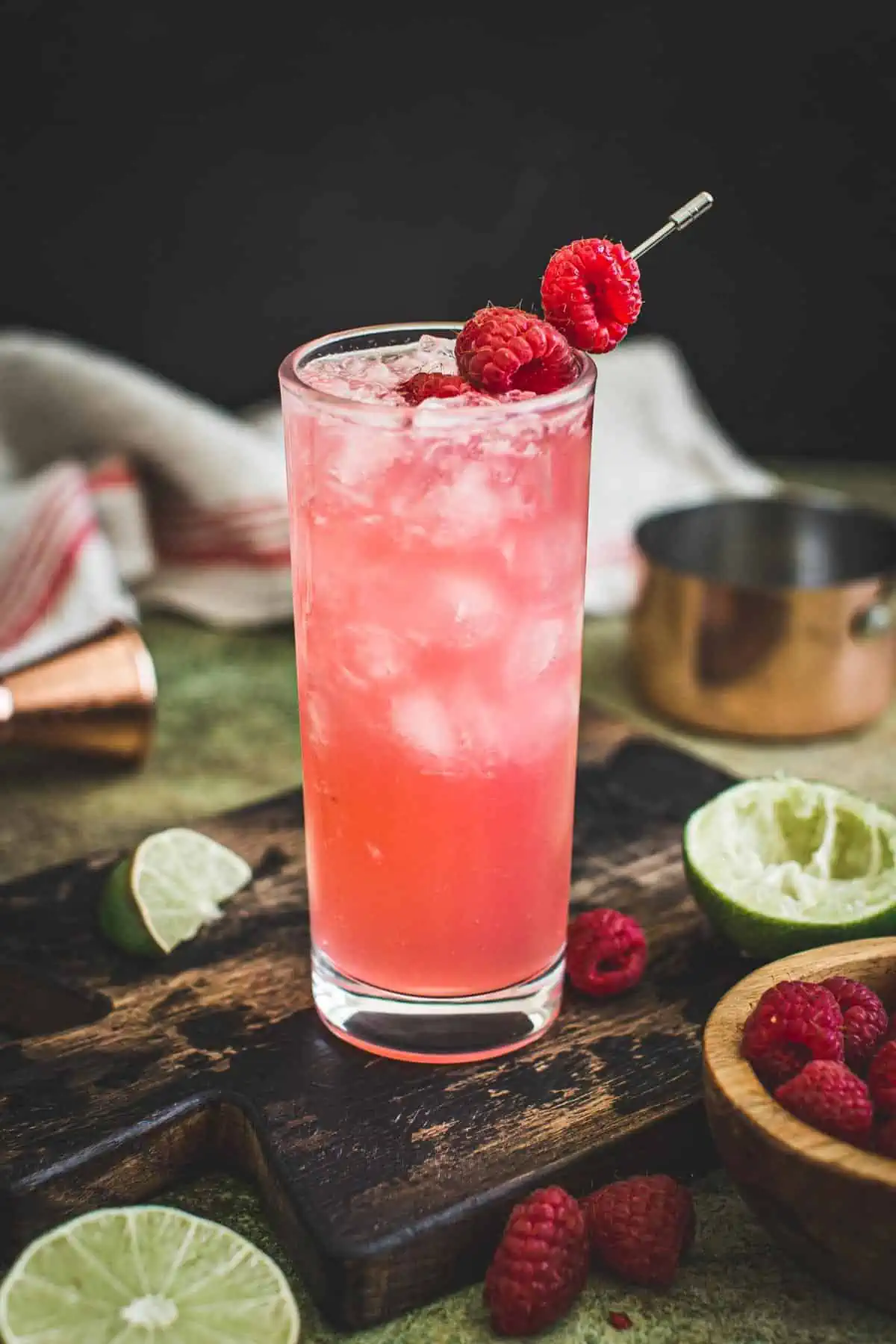 Floradora cocktail in a tall glass with raspberries for garnish.