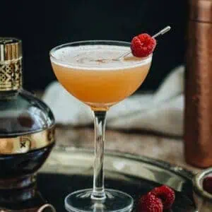 French Martini in a coupe glass with a fresh raspberry for garnish.