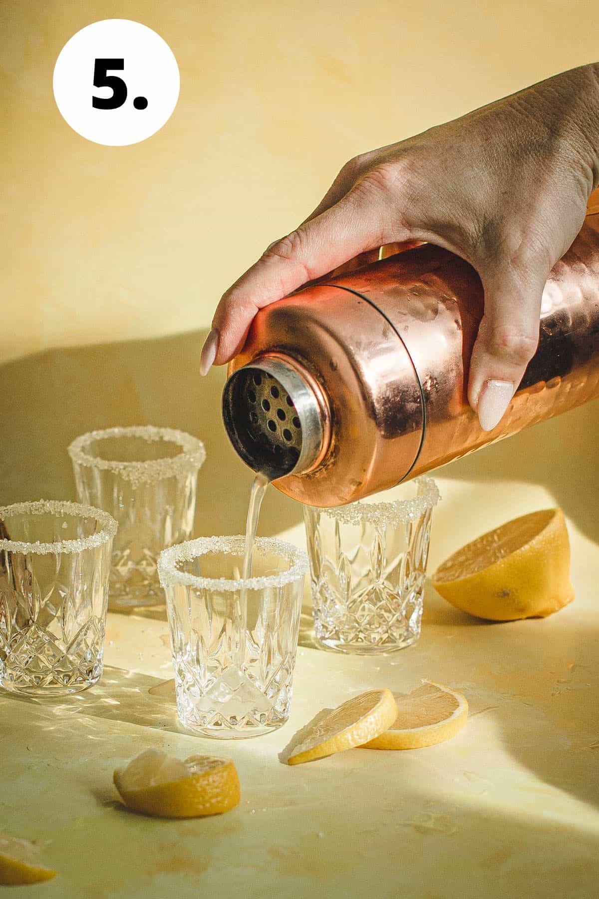 Cocktail shaker straining a shot into a shot glass.