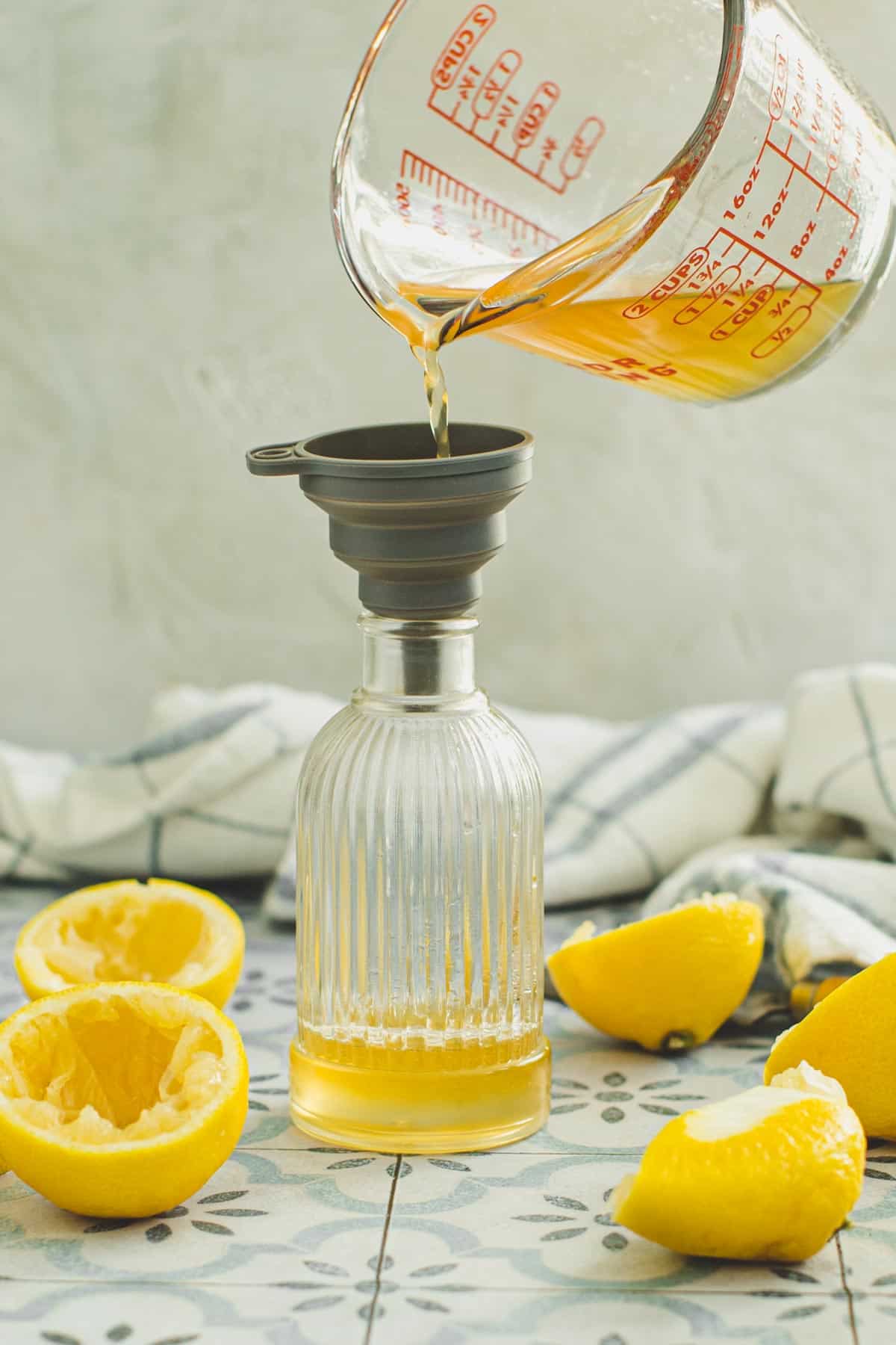 Lemon simple syrup being poured into a bottle.
