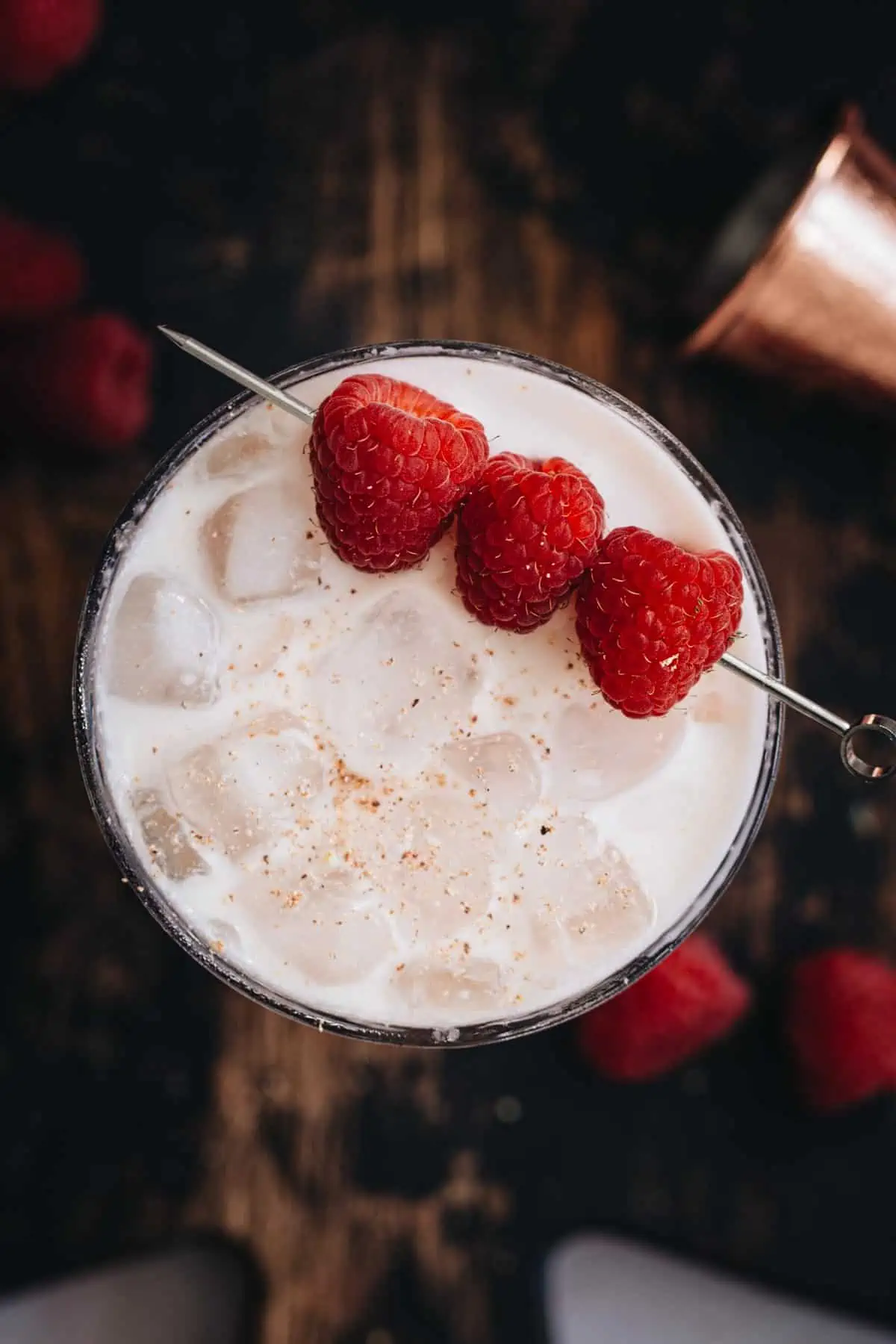 Nuts and berries cocktail topped with nutmeg and garnished with fresh raspberries.