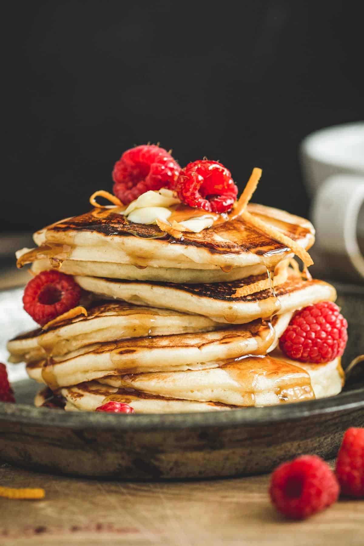 Maple syrup infused pancakes topped with fresh raspberries and orange peel.