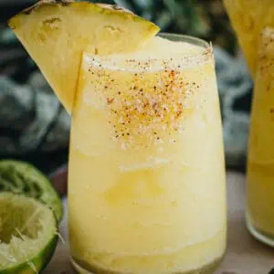 Frozen pineapple margarita with a salted rim and pineapple wedge for garnish.