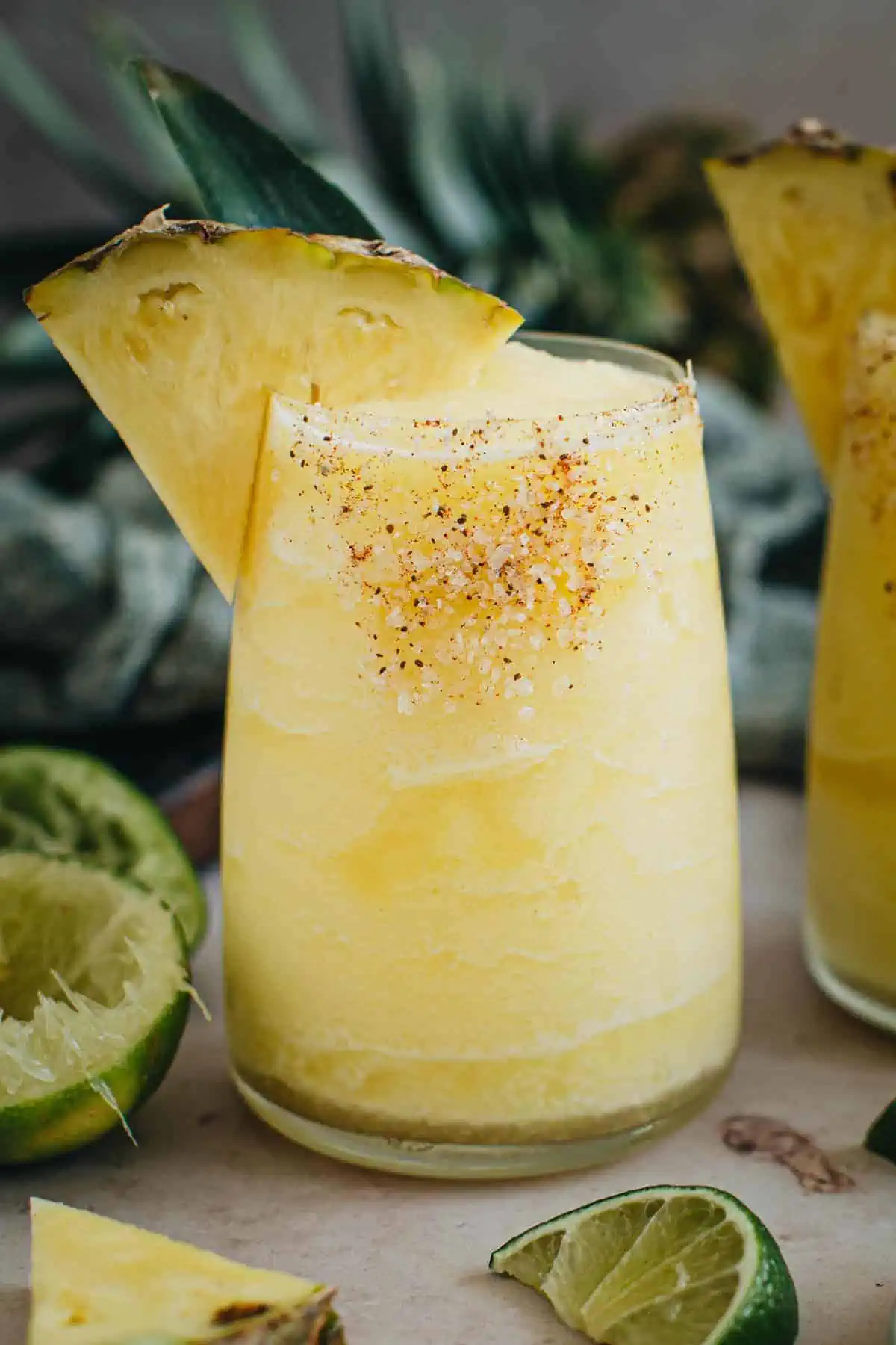 Frozen pineapple margarita with a salted rim an pineapple wedge for garnish.