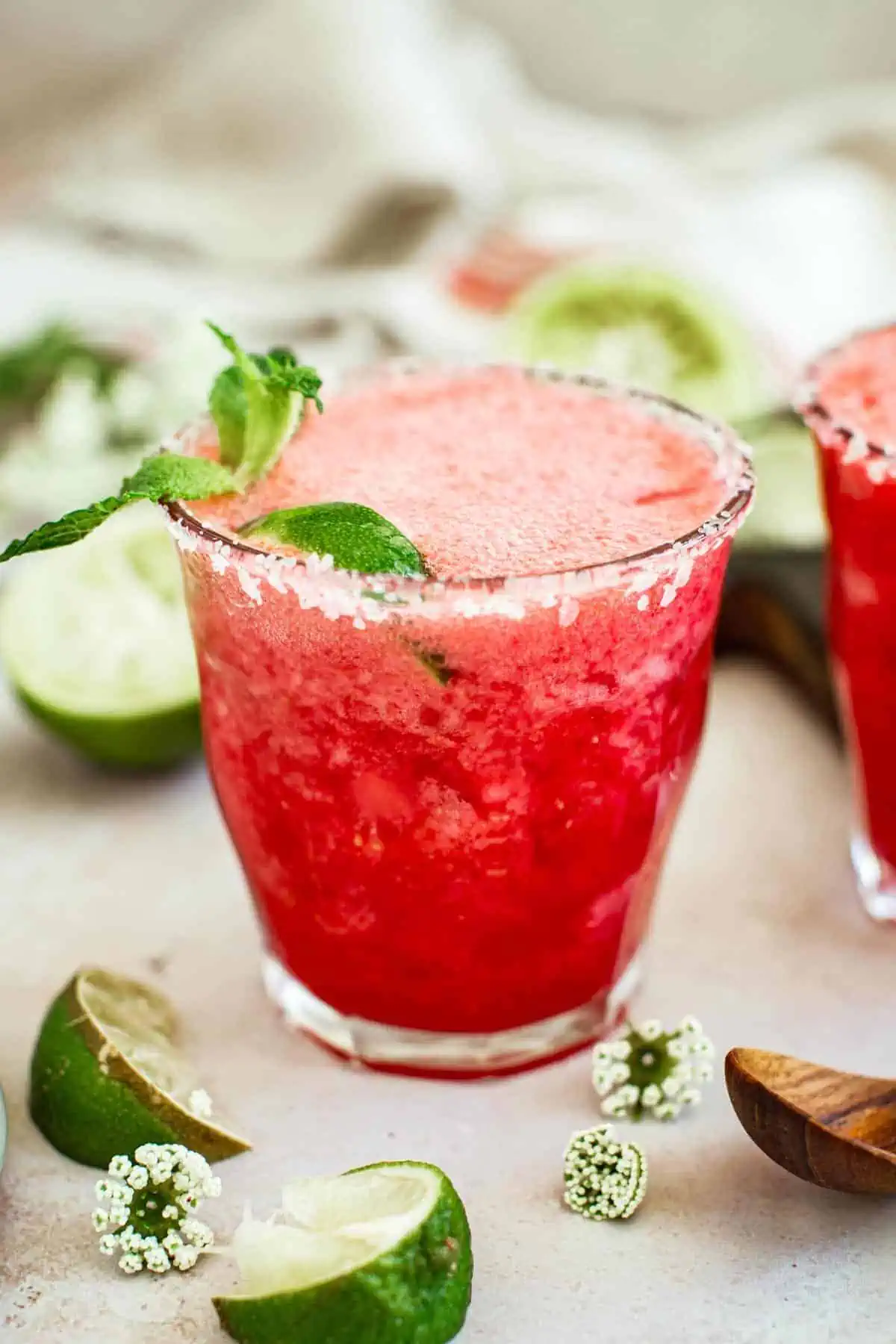 Raspberry margarita with a salted rim and a lime wedge.