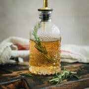 Rosemary simple syrup in a bottle with a spout.