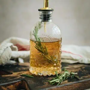 Rosemary simple syrup in a bottle with a spout.