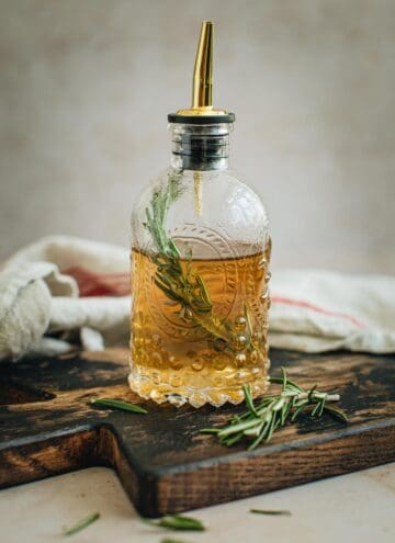 Rosemary simple syrup in a bottle with a spout.