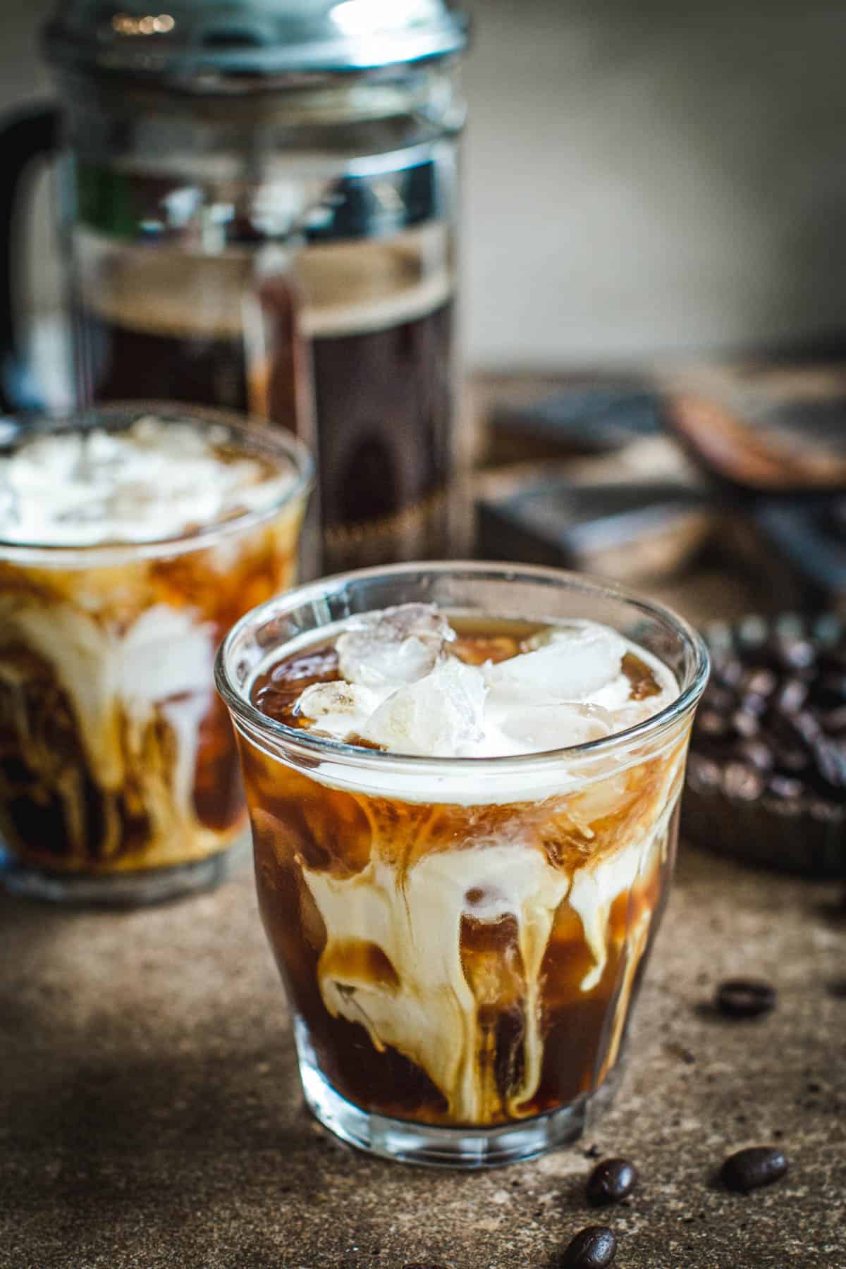 French press iced coffee in a glass with cream.