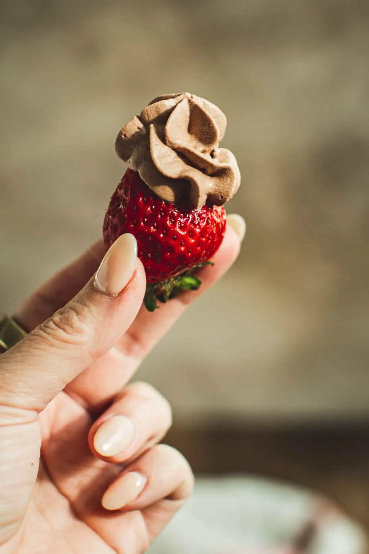 Chocolate whipped cream on top of a strawberry.