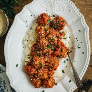 Meatballs and rice on a platter with a serving spoon.