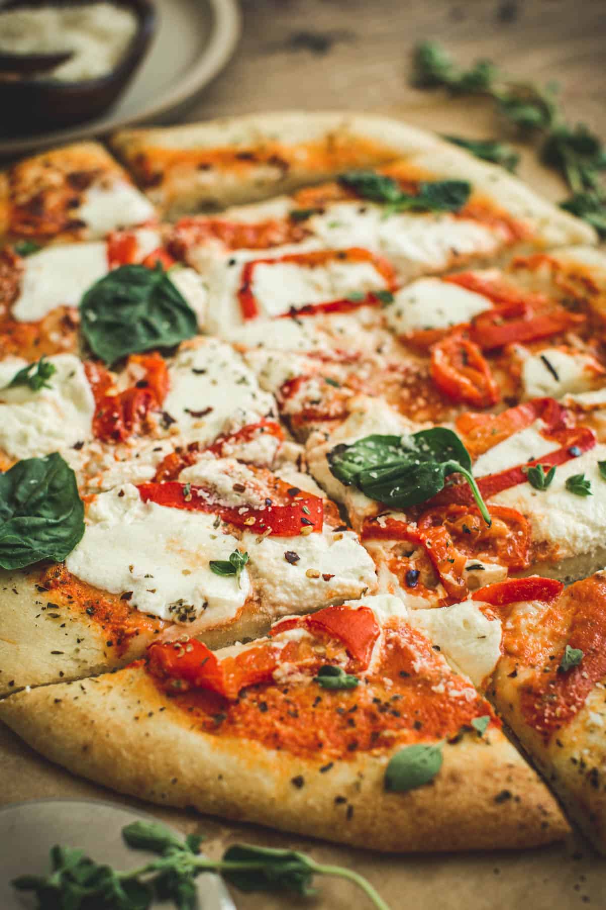 Roasted red pepper pizza sliced and topped with fresh basil.