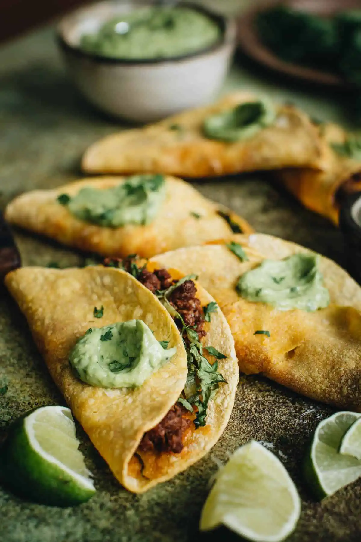 Crispy beef tacos topped with avocado crema.