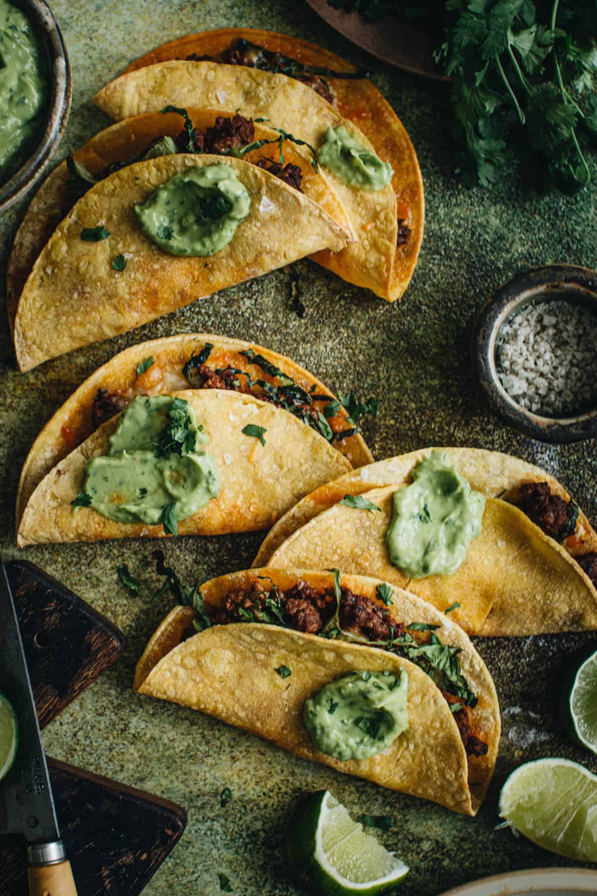 Baked crispy tacos topped with avocado crema.