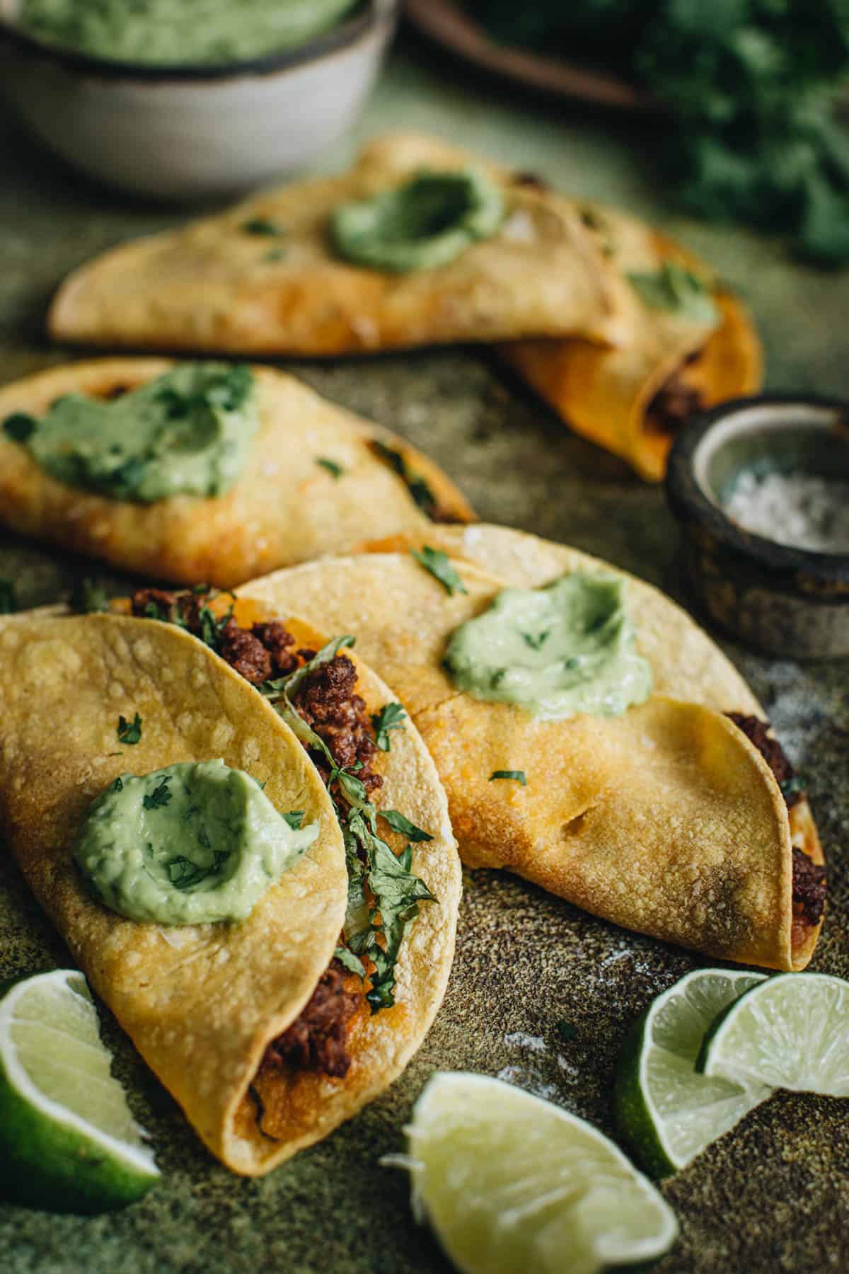 Crispy tacos topped with avocado crema.