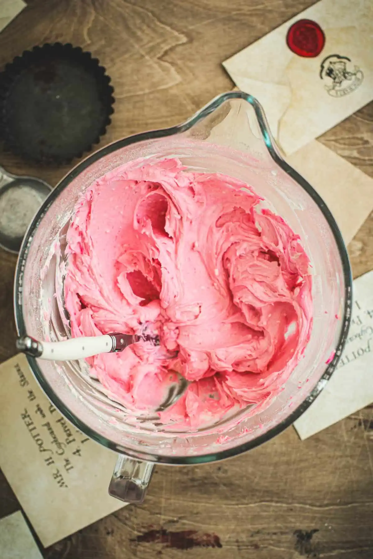 Pink frosting in a bowl with a spoon.