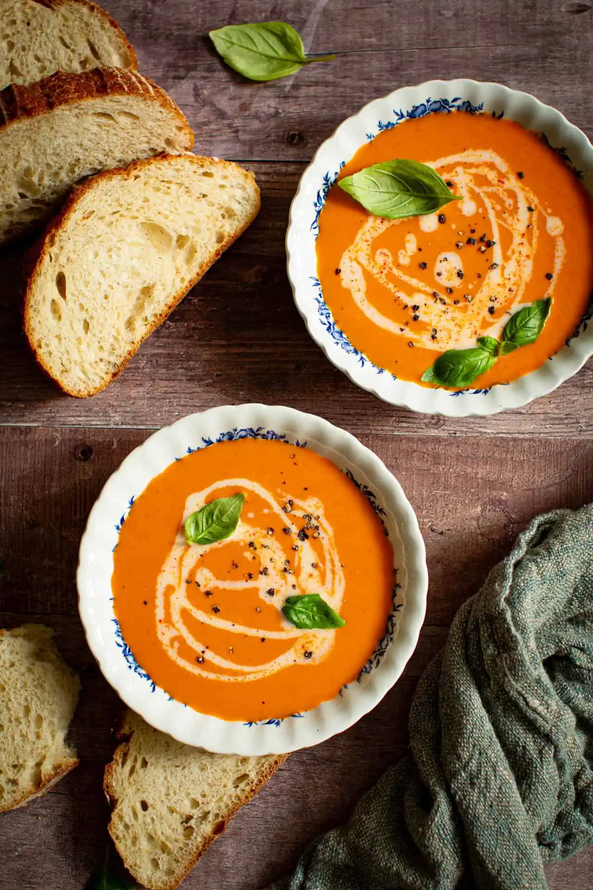 Spicy tomato soup in bowls topped with fresh basil.