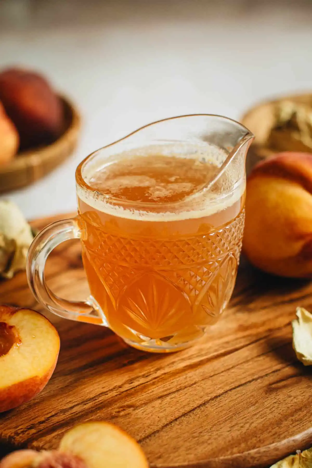 Peach simple syrup in a glass cup.