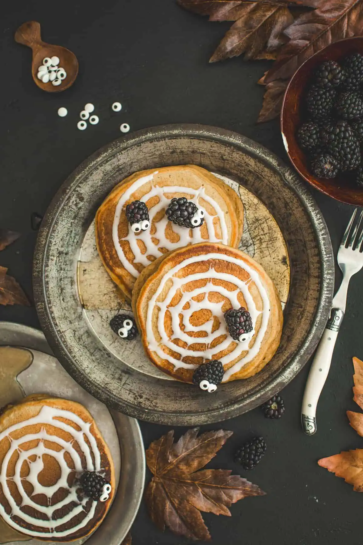 Pancakes for halloween with icing spider webs and blackberry spiders.