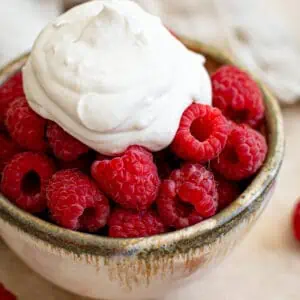 Vegan whipped cream on top of raspberries.