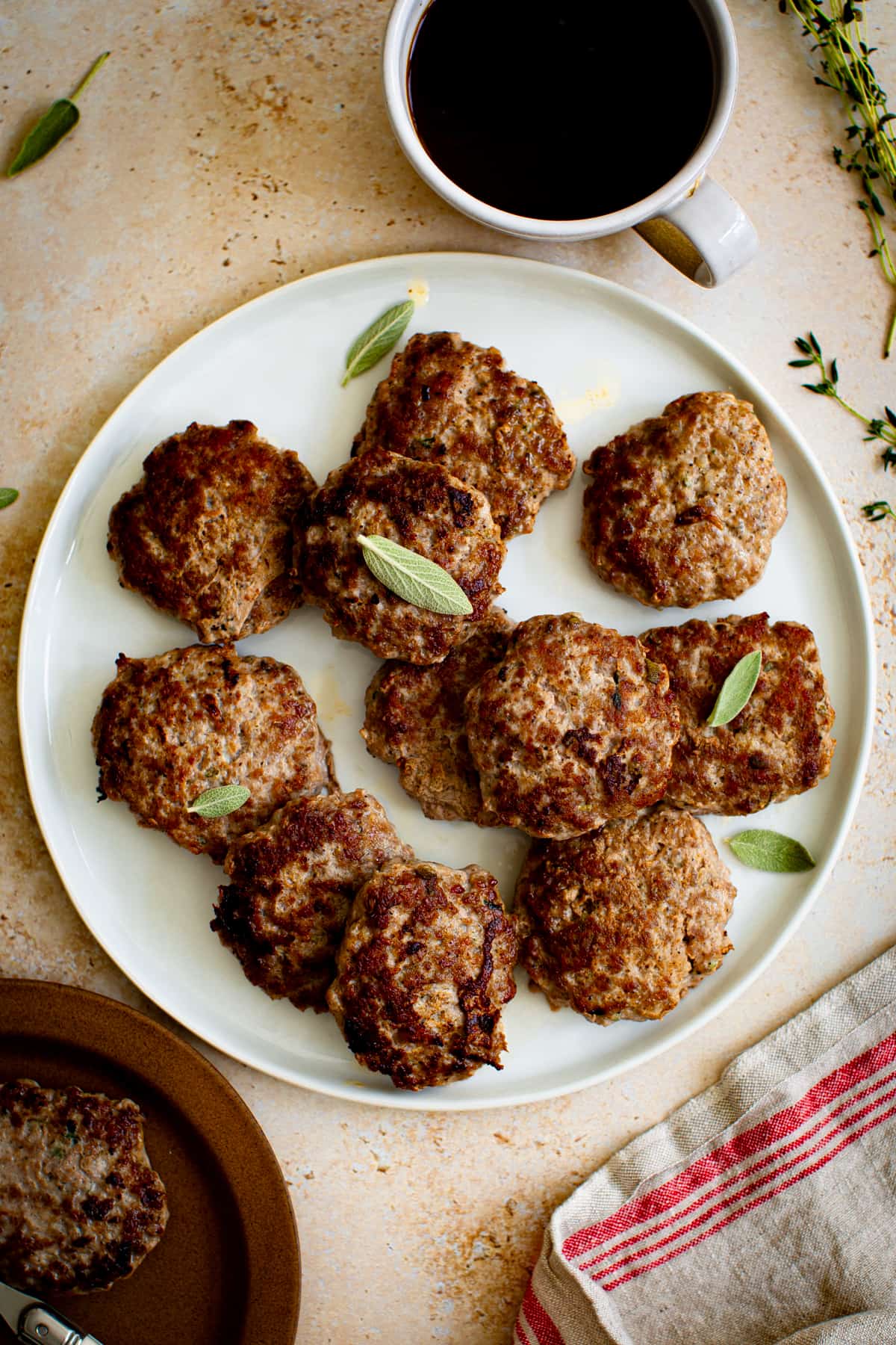 Breakfast sausage on a plate with fresh sage.