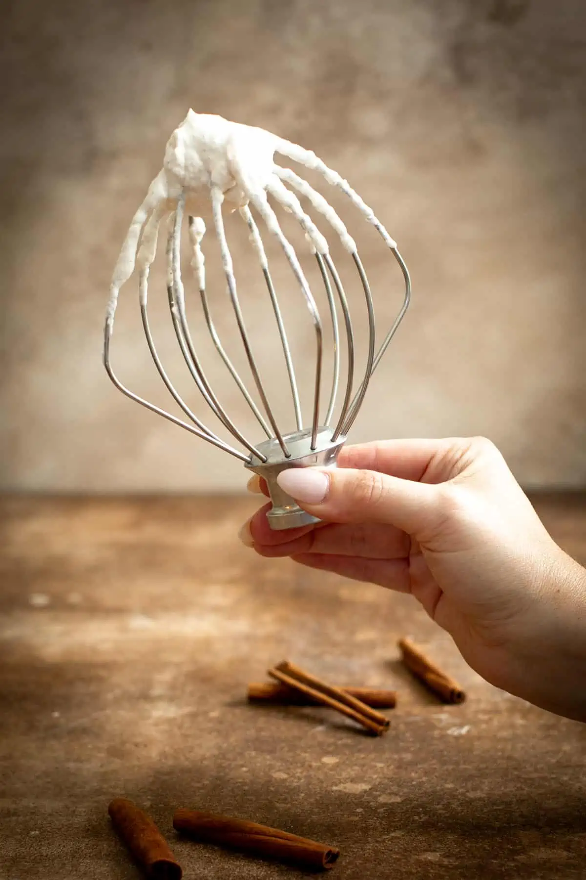 Cinnamon whipped cream on the whisk attachment of a stand mixer.