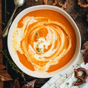 Pumpkin tomato soup with cream drizzled on top.