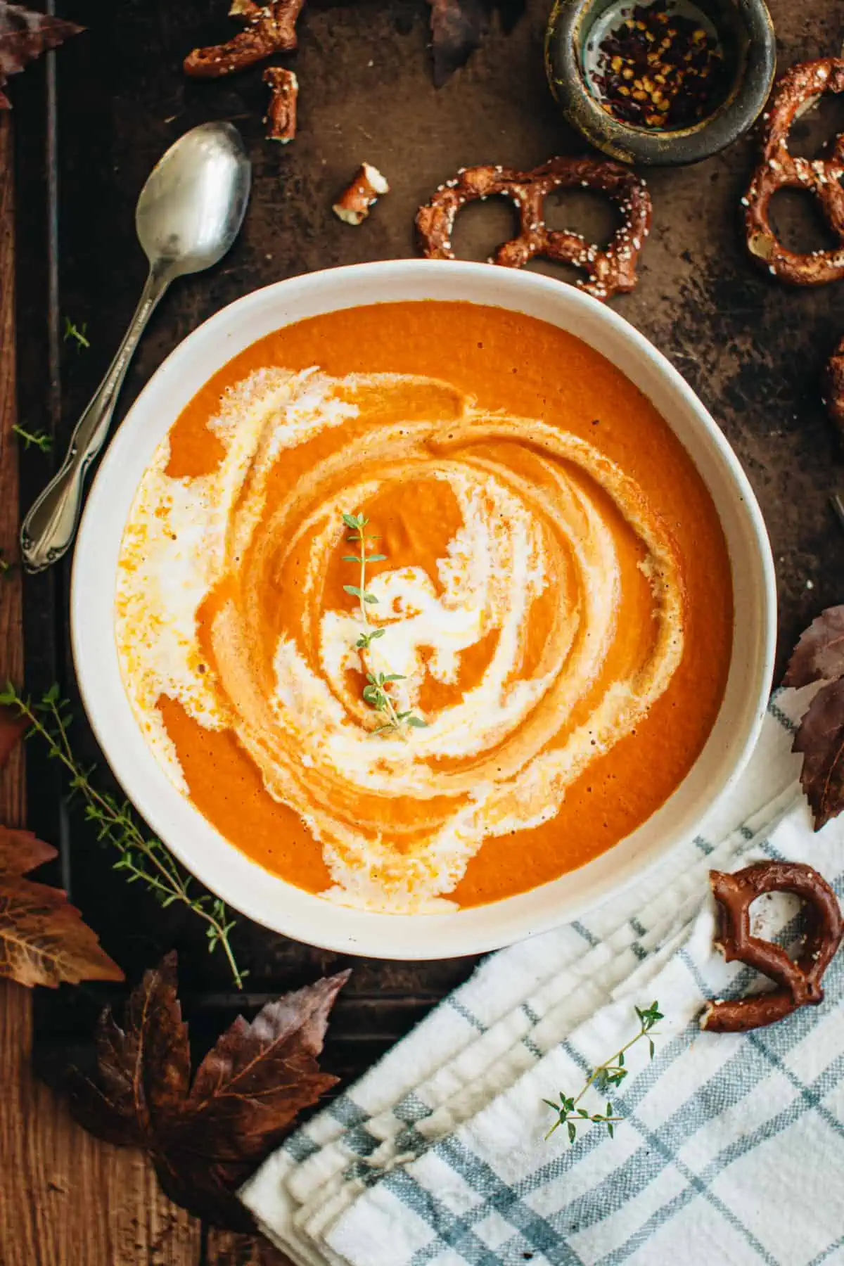 Pumpkin tomato soup in a bowl with a cream swirl on top.