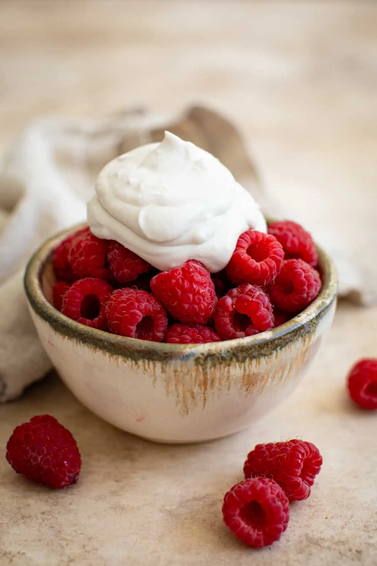 Vegan whipped cream on top of raspberries.