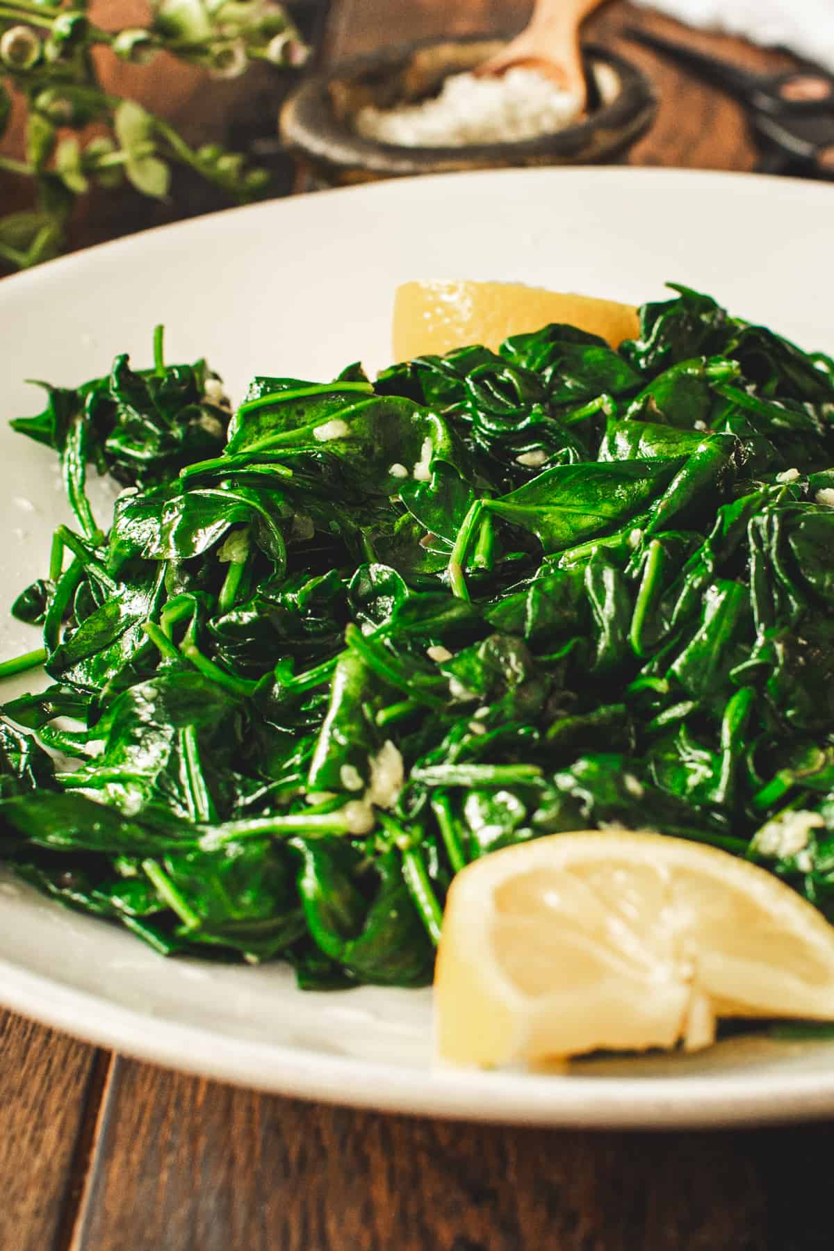 Sauteed spinach with garlic and fresh squeezed lemon juice on a white plate.