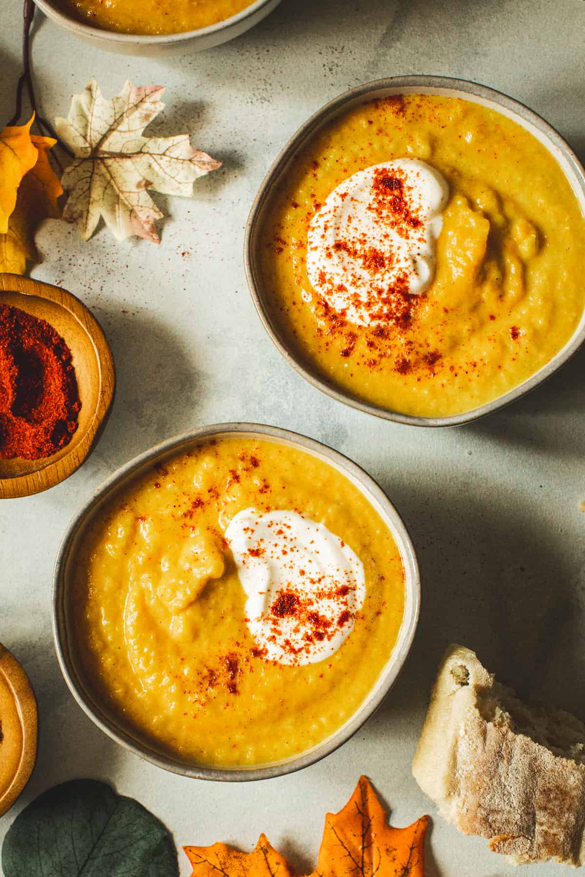 Acorn squash soup in appetizer bowls topped with sour cream and paprika.