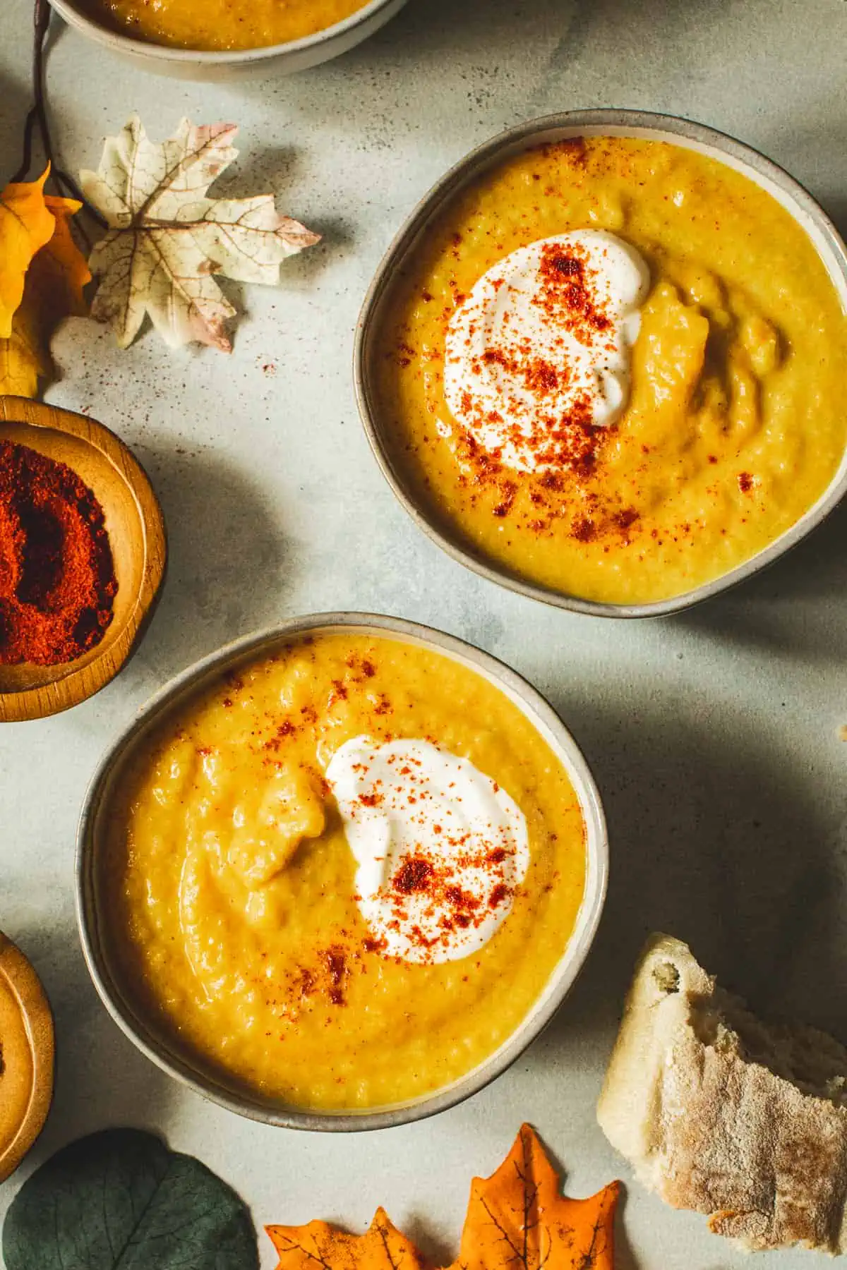 Acorn squash soup in appetizer bowls topped with sour cream and paprika.